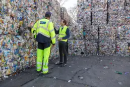 Zwei Personen zwischen Abfallballen in Recyclinganlage, Interzero, 2026